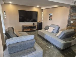 a living room with two couches and a flat screen tv at Maison des Ramiers in Saint-Paul