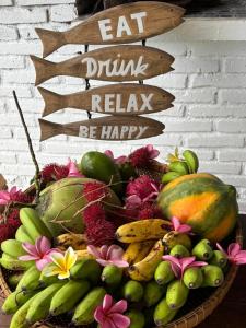 a basket of fruit with a sign that reads eat drink relax be happy at Lombok Coconut Hotel in Mangsit