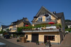 a large yellow building with a balcony with red umbrellas at Weingut Sauer-Kettermann in Enkirch