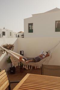 a man laying in a hammock on a balcony at Vivilanza Surfhouse in Costa Teguise