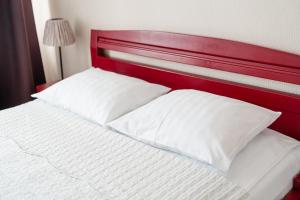 a bed with white pillows and a red headboard at Hotel Mezaparks in Riga