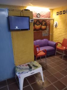 ein Wohnzimmer mit einer Couch und einem Fernseher an der Wand in der Unterkunft Hostal ROLLED in Villavieja