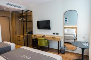 a room with a bed and a desk with a television at Mece Hotel Tirana in Tirana