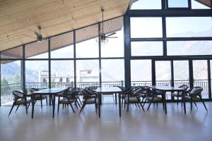 a group of tables and chairs in a room with windows at Alpine Vista Wellness & Resort in Gupta Kāshi