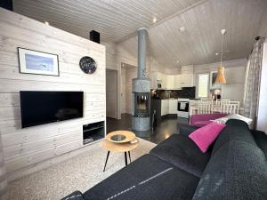 a living room with a black couch and a fireplace at Lumilyhty B in Äkäslompolo
