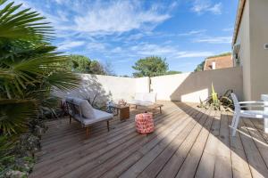 a wooden deck with chairs and tables on a house at Les Mimosas in Ronce-les-Bains
