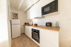 a kitchen with white cabinets and a microwave and a refrigerator at Les Mimosas in Ronce-les-Bains +24 photos