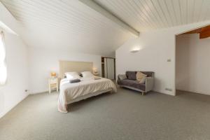 a white bedroom with a bed and a chair at Les Mimosas in Ronce-les-Bains