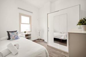 a white bedroom with a mirror and a bed at Apartamento Sa Mesquida 9 by 3VILLAS in Cala Llonga