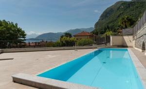a large blue swimming pool with mountains in the background at Casa Julia - Menaggio by LoveComo in Menaggio