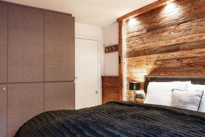 a bedroom with a wooden wall next to a bed at StAnton Snow in Sankt Anton am Arlberg