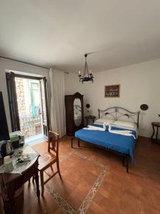 a bedroom with a blue bed and a table at B&B Mirabella Rooms Ortigia in Syracuse