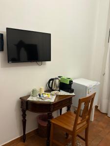 a room with a table with a television on a wall at B&B Mirabella Rooms Ortigia in Syracuse