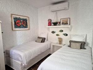 two beds in a room with white walls at Casita Pablo in Agua Amarga