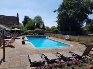 a swimming pool in a yard with chairs and a table at The Old Stone Barn in Warrington