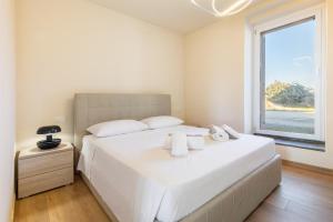 a bedroom with a large white bed with towels on it at Hostdomus - Residenza La Vigna in Dogliani