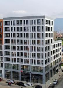a white building with cars parked in front of it at Mece Hotel Tirana in Tirana