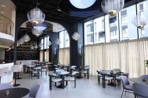 a restaurant with tables and chairs and windows at Mece Hotel Tirana in Tirana