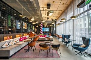 a lobby with tables and chairs in a building at Moxy Kaunas Center in Kaunas