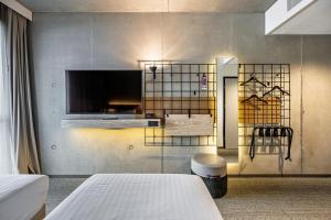 a room with two beds and a tv on a wall at Moxy Kaunas Center in Kaunas