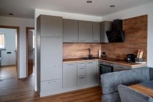 a kitchen with white cabinets and wooden floors at Moderne Ferienwohnung nahe Salzburg & Eugendorf in Eugendorf +14 photos