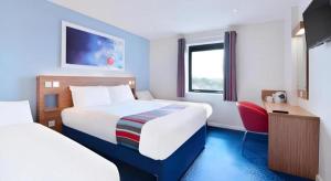 a hotel room with two beds and a red chair at Travelodge Middlesbrough in Middlesbrough