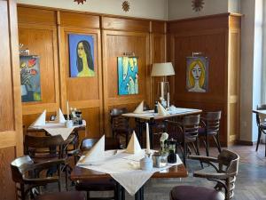 a restaurant with tables and chairs and paintings on the walls at Strandhotel Sonnenburg by ANS in Kühlungsborn