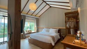 a bedroom with a bed and a large window at Chang'E Villa Rakthai in Ban Rak Thai