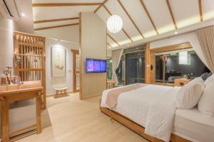 a bedroom with a bed and a desk and a television at Chang'E Villa Rakthai in Ban Rak Thai