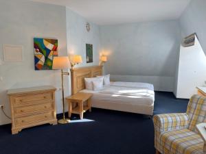 a bedroom with a bed and a desk and a chair at Strandhotel Sonnenburg by ANS in Kühlungsborn +69 photos