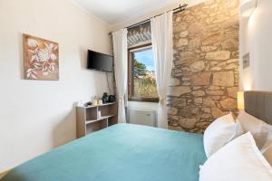a bedroom with a blue bed and a stone wall at Bosa Eye House 1873 in Bosa