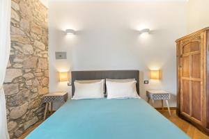 a bedroom with a blue bed and a stone wall at Bosa Eye House 1873 in Bosa