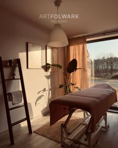 a room with a bed and a window with a lamp at ArtFolwark Wojnowo in Wojnówko
