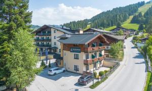 a town in the mountains with cars parked in a parking lot at Hotel Kirchboden by Alpeffect Hotels in Wagrain