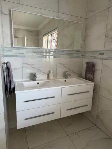 a white bathroom with a sink and a mirror at Plattekloof Mountain view in Plattekloof