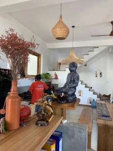 a man in a kitchen with a statue on a table at Dreamers Surf House in Matara