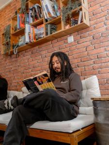 a man sitting on a couch reading a book at Olé Backpackers Hostel in Alicante