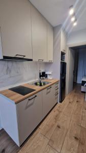 a kitchen with white cabinets and a wooden floor at 3 Keys Luxury Apartment in Nikiana