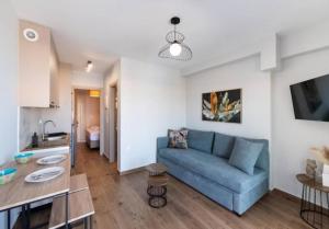 a living room with a blue couch and a kitchen at 3 Keys Luxury Apartment in Nikiana