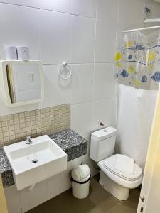 a white bathroom with a sink and a toilet at Hotel Econômico in Volta Redonda