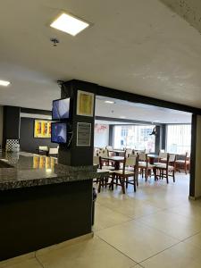 a restaurant with tables and chairs and a bar with televisions at Hotel Econômico in Volta Redonda