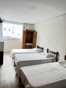 a group of four beds in a room at Hotel Econômico in Volta Redonda