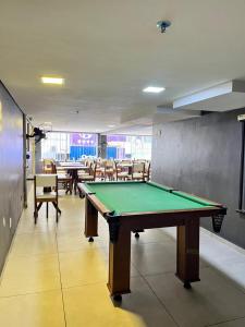 a pool table in a room with tables and chairs at Hotel Econômico in Volta Redonda