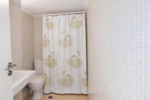 a bathroom with a shower curtain with a toilet and a sink at Beachfront Absolute Bliss in Perigiali, Korinthia in Periyiálion