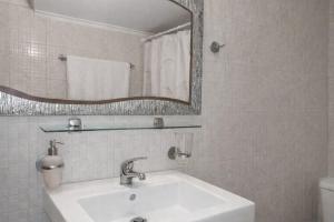 a white bathroom with a sink and a mirror at Beachfront Absolute Bliss in Perigiali, Korinthia in Periyiálion