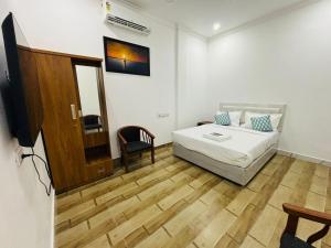 a bedroom with a bed and a tv and a chair at MIRACLE Inn in Alwaye