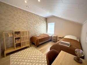a bedroom with two beds and a table and a window at Riihen Vintti in Äkäslompolo