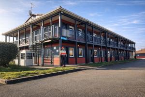 a woman is standing in front of a building at Enzo Hotels Chartres Mainvilliers in Chartres