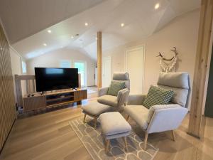 a living room with two chairs and a flat screen tv at Riihen Vintti in Äkäslompolo +2 photos