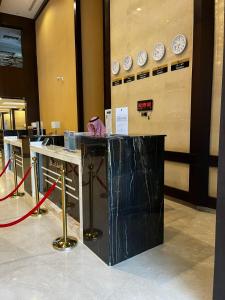 a lobby with a counter with clocks on the wall at Elaf Al Sagryah Hotel in Mecca